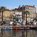 A promenade next to a harbor filled with boats and lined by sidewalk cafes and beach residences